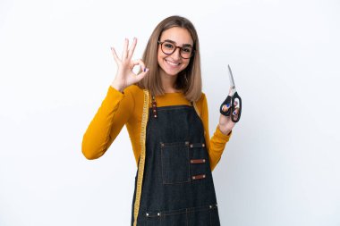 Beyaz arka planda izole edilmiş beyaz tenli dikiş kutusu kadını parmaklarıyla tamam işareti gösteriyor.