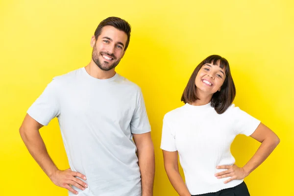 Young Couple Isolated Yellow Background Posing Arms Hip Smiling — Stock fotografie
