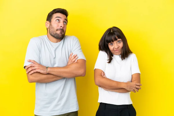 Young Couple Isolated Yellow Background Making Doubts Gesture While Lifting — Foto de Stock