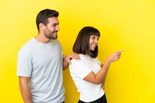 Young Couple Isolated Yellow Background Pointing Side Present Product — Stock fotografie