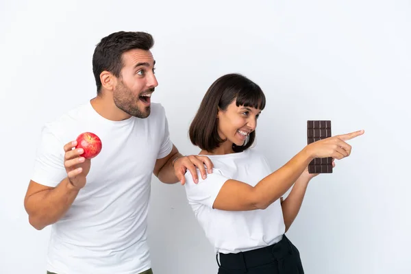 Young Couple Holding Chocolate Apple Isolated White Background Pointing Side — Stockfoto