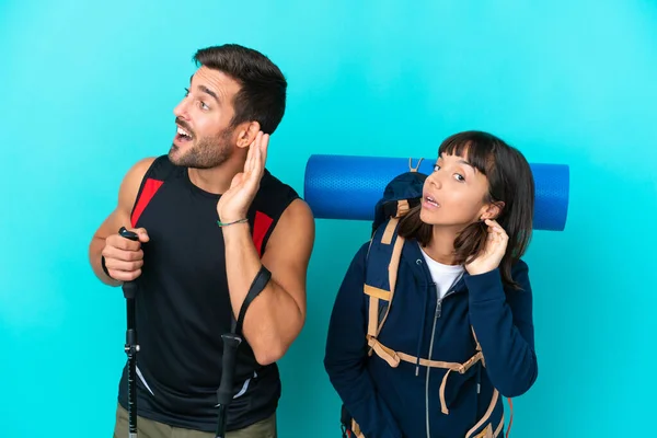 Young Mountaineer Couple Big Backpack Isolated Blue Background Listening Something — Stockfoto