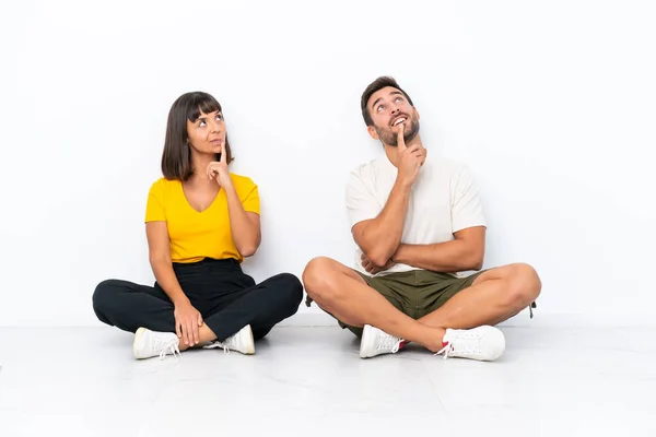 Young Couple Sitting Floor Isolated White Background Thinking Idea While — Fotografia de Stock