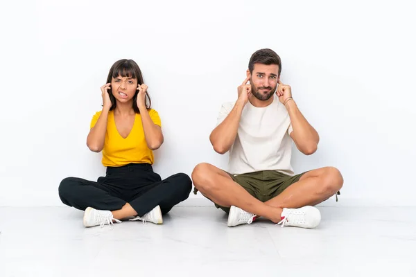 Young Couple Sitting Floor Isolated White Background Covering Both Ears — Fotografia de Stock