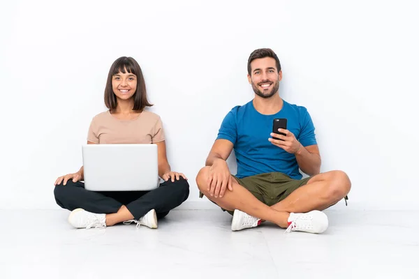 Young Couple Sitting Floor Holding Mobile Phone Isolated White Background — Photo