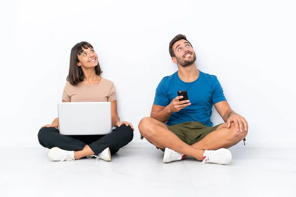 Young Couple Sitting Floor Holding Mobile Phone Isolated White Background — 图库照片