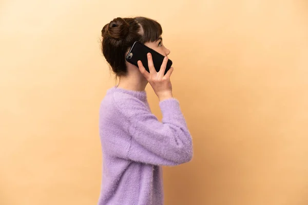 Menina Caucasiana Isolado Fundo Bege Mantendo Uma Conversa Com Telefone — Fotografia de Stock