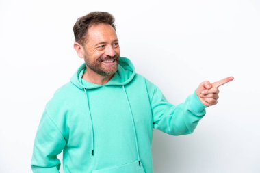Beyaz arka planda izole edilmiş orta yaşlı beyaz bir adam parmağını yana uzattı ve bir ürün sundu.