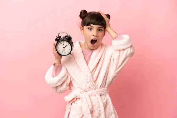 Маленькая Белая Девочка Изолированная Розовом Фоне Пижаме Держащая Часы Удивленным — стоковое фото