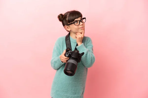 Little Photographer Girl Isolated Pink Background Having Doubts While Looking —  Fotos de Stock