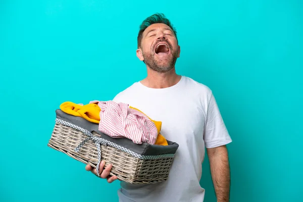 Middelbare Leeftijd Vrouw Met Een Kledingmand Geïsoleerd Blauwe Achtergrond Lachen — Stockfoto