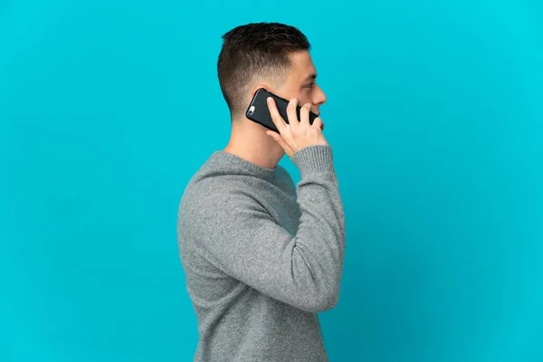 Młody Biały Człowiek Odizolowany Niebieskim Tle Prowadzenie Rozmowy Telefon Komórkowy — Zdjęcie stockowe