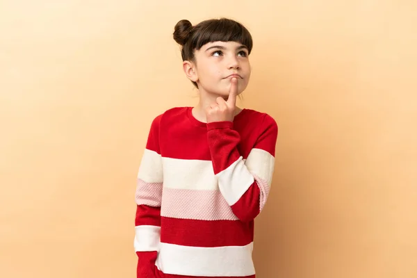 Little Caucasian Girl Isolated Beige Background Having Doubts While Looking — Fotografia de Stock