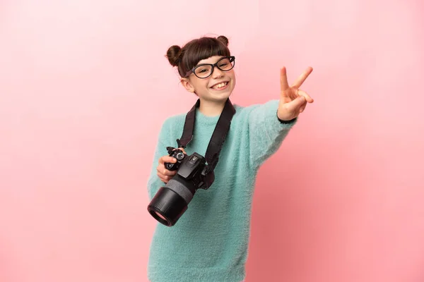 Pequeña Fotógrafa Aislada Sobre Fondo Rosa Sonriendo Mostrando Signo Victoria —  Fotos de Stock