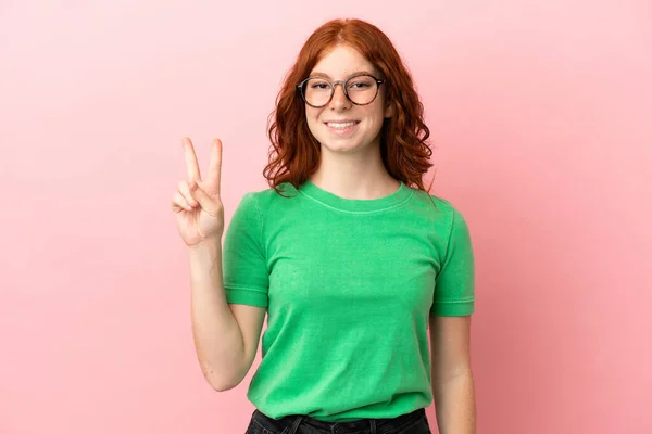 Adolescente Rossa Ragazza Isolato Sfondo Rosa Sorridente Mostrando Segno Vittoria — Foto Stock