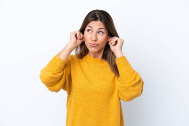 Beyaz arka planda izole edilmiş orta yaşlı beyaz kadın hayal kırıklığına uğramış ve kulaklarını kapatmış.