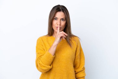 Beyaz arka planda izole edilmiş orta yaşlı beyaz kadın parmağını ağzına koyan sessizlik işareti gösteriyor.