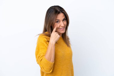 Beyaz arka planda izole edilmiş orta yaşlı beyaz kadın bir şey gösteriyor.
