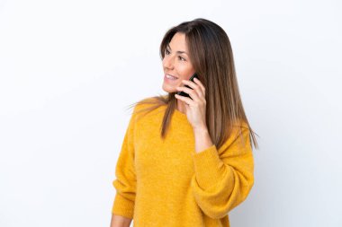 Beyaz arka planda izole edilmiş orta yaşlı beyaz bir kadın cep telefonuyla sohbet ediyor.