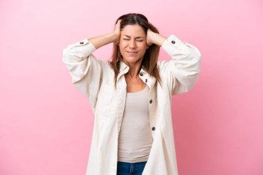 Pembe arka planda izole edilmiş orta yaşlı beyaz kadın hayal kırıklığına uğramış ve kulaklarını kapatmış.