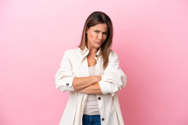 Pembe arka planda izole edilmiş orta yaşlı beyaz kadın üzgün hissediyor.