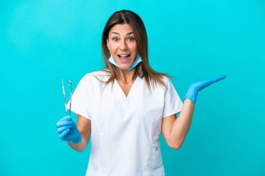 Yüzünde şok ifadesi olan orta yaşlı bir kadın doktor mavi arka planda izole edilmiş.