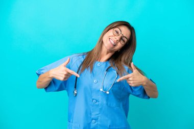 Orta yaşlı cerrah kadın, mavi arka planda soyutlanmış gururlu ve kendini beğenmiş.