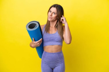 Spor kadını yoga derslerine giderken elinde paspas tutarken sarı olmayan arka planda şüphe uyandırıyor.