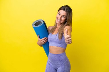 Elinde paspas tutarken yoga derslerine giden sporcu kadın sarı olmayan bir arkaplanı başparmakla izole etti çünkü iyi bir şey oldu.