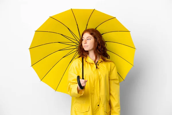 ティーンRedhead女の子レインプルーフコートと傘隔離上の白い背景見にザ側 — ストック写真