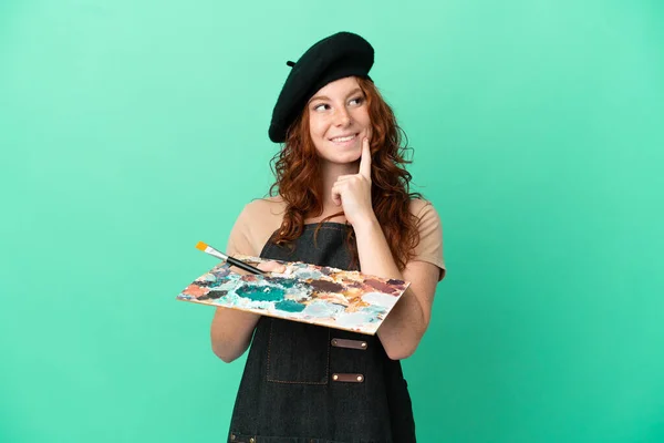 Nastoletni Rudowłosy Artysta Trzymając Paletę Odizolowanych Zielonym Tle Myśląc Pomysł — Zdjęcie stockowe