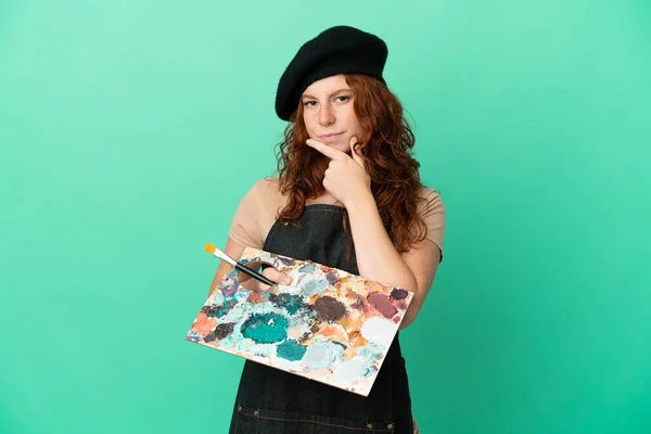 Teenager Redhead Artist Holding Palette Isolated Green Background Thinking — Zdjęcie stockowe