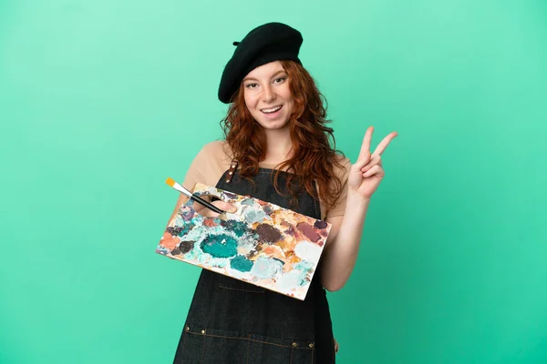 Teenager Rusovláska Umělec Drží Paletu Izolované Zeleném Pozadí Úsměvem Ukazuje — Stock fotografie