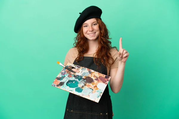 Teenager Redhead Artist Holding Palette Isolated Green Background Showing Lifting — Zdjęcie stockowe