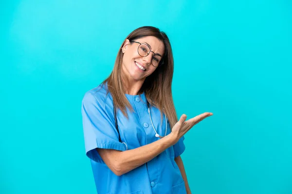 中年妇女外科医生在蓝色背景下孤立无援 面带微笑地看着 — 图库照片