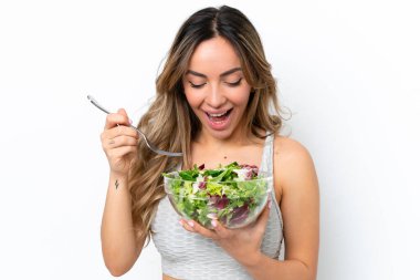 Beyaz arka planda izole edilmiş beyaz bir kadın elinde mutlu bir ifadeyle bir kase salata tutuyor.