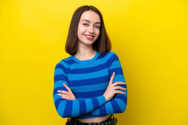 Sarı arka planda izole edilmiş genç Ukraynalı kadın kollarını kavuşturup ileriye bakıyor.