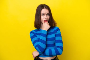 Sarı arka planda izole edilmiş genç Ukraynalı kadının şüpheleri var.