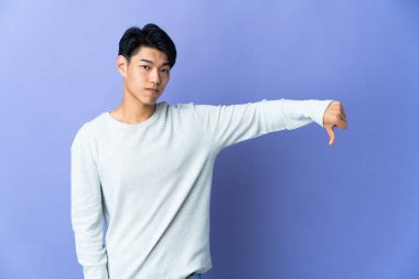 Mor arka planda izole edilmiş genç bir Çinli başparmağının negatif ifadesini gösteriyor.