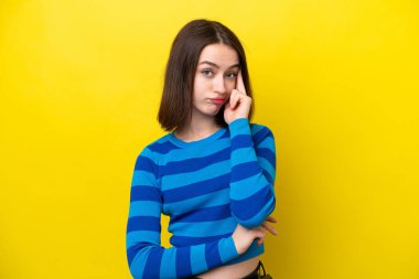 Genç Ukraynalı kadın sarı arka planda izole edilmiş bir fikir düşünüyor.