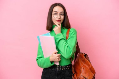 Genç öğrenci Ukraynalı kadın pembe arka planda izole edilmiş düşünüyor.