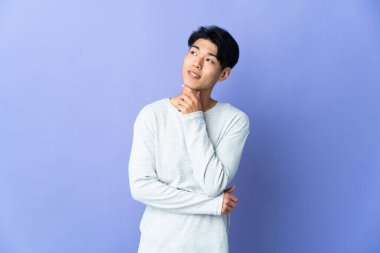 Mor arka planda izole edilmiş genç bir Çinli gülümserken yukarı bakıyor.