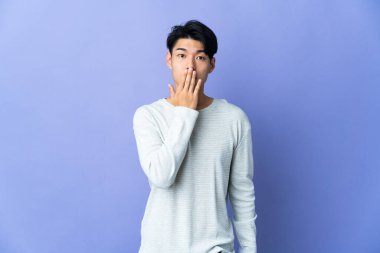 Mor arka planda izole edilmiş genç bir Çinli ağzı eliyle kapatıyor.