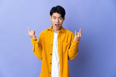 Mor arka planda izole edilmiş genç bir Çinli boynuz hareketi yapıyor.