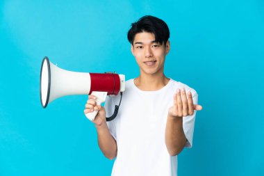 Genç Çinli bir adam mavi arka planda izole edilmiş elinde bir megafon ve davet edici bir el ile geliyor.