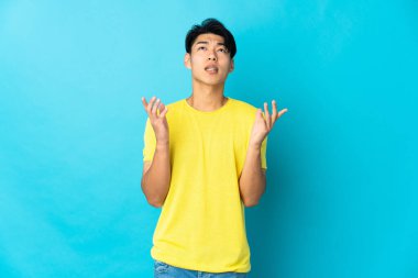 Mavi arka planda izole edilmiş genç bir Çinli bunalımda.