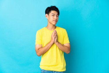 Genç Çinli bir adam mavi arka planda bir şeyler çeviriyor.