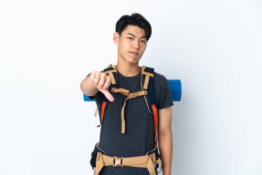 Dağcı Çinli adam, beyaz arka planda izole edilmiş, negatif ifadeyle baş parmağını aşağı gösteriyor.