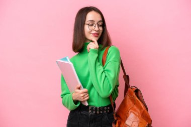 Genç öğrenci Ukraynalı kadın pembe arka planda izole edilmiş. Yan tarafa bakıyor ve gülümsüyor.