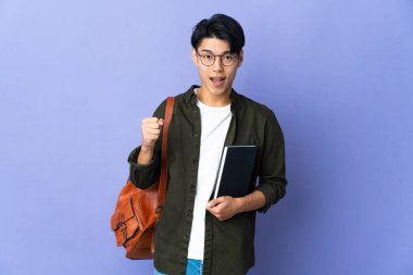 Mor arka planda izole edilmiş genç bir öğrenci zaferi kutluyor.